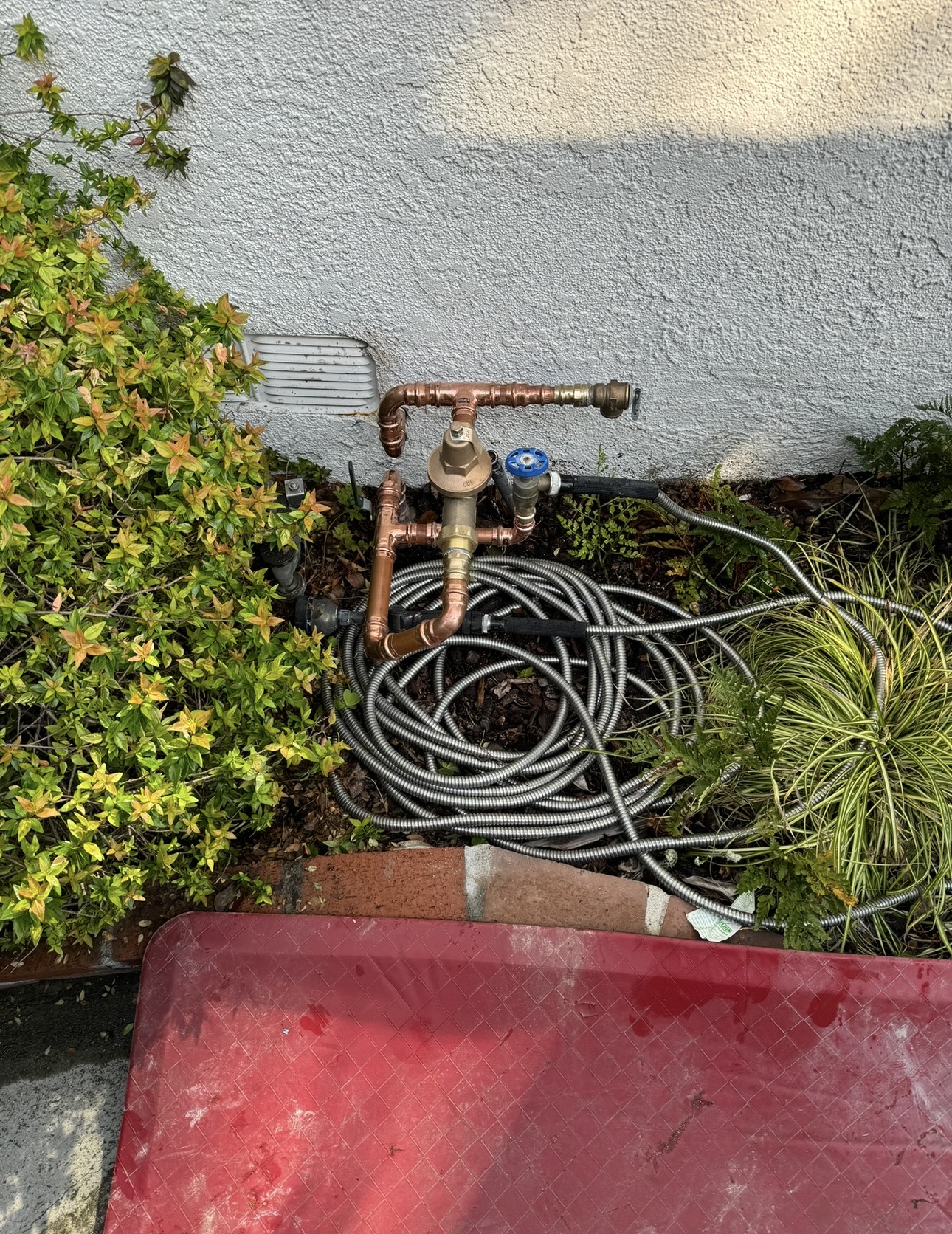 Exterior main water manifold with pressure regulator, relief valve, and shutoff components.