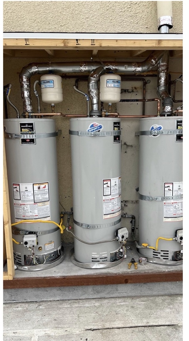 Three commercial water heaters with connected plumbing.