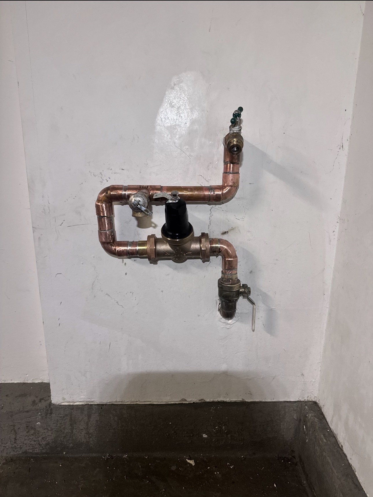 Wall-mounted copper water line assembly with brass pressure regulator, relief valve, and shutoff valve