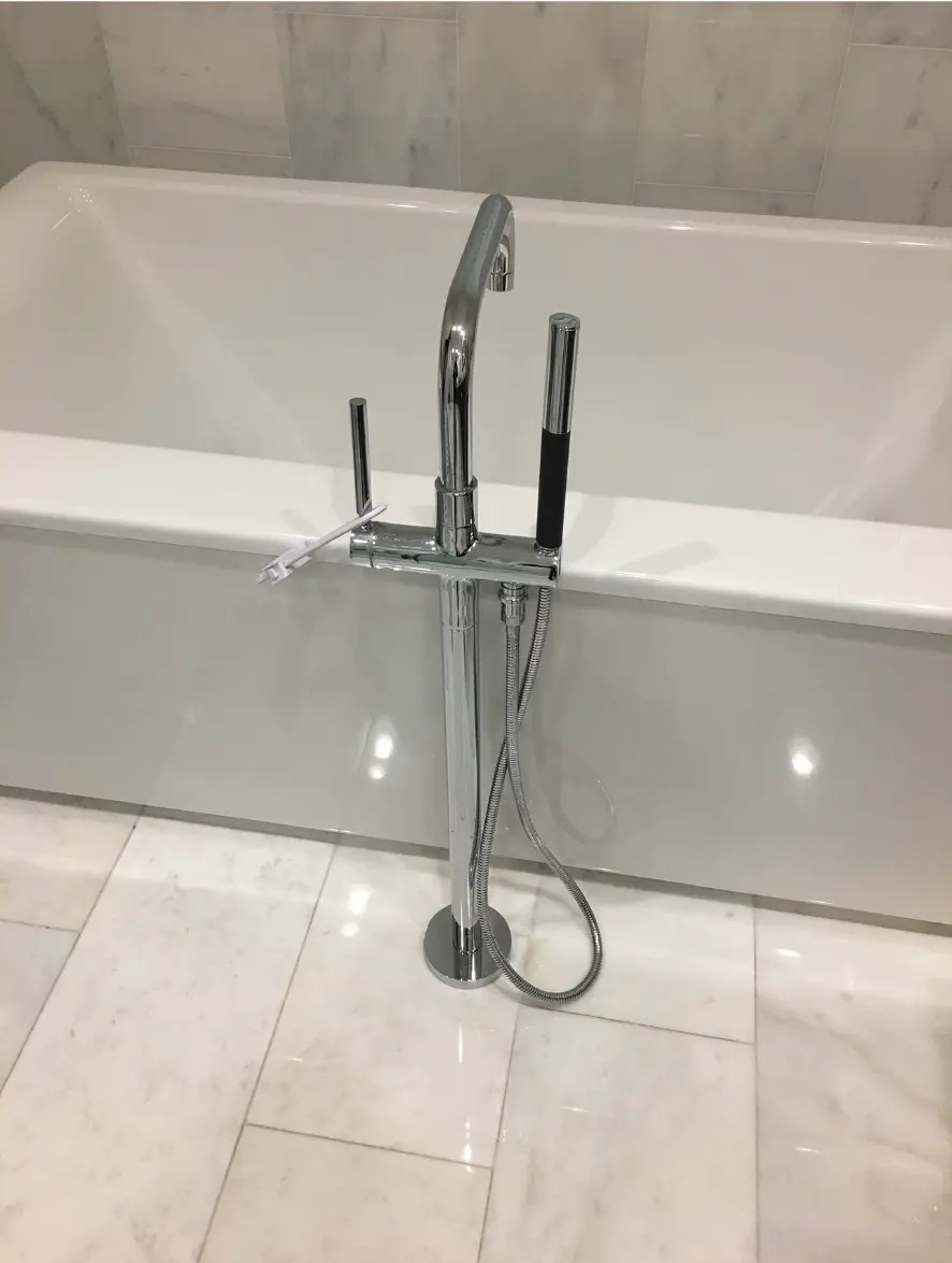 Freestanding bathtub with chrome floor-mounted plumbing fixture
